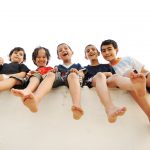 Children sitting on wall, happy boys laughing