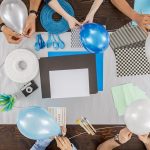 Group of friends sitting together at the table and preparing the party decorations