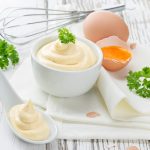 Mayonnaise in bowl on wooden table