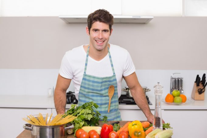 cooking Young man with vegetables standing in the kitchen at home