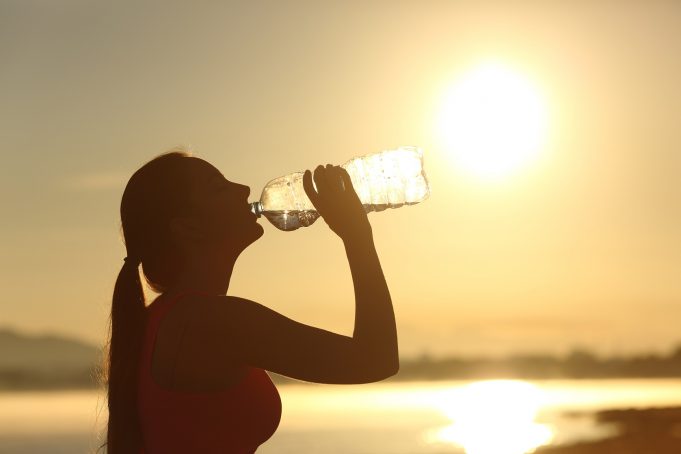 Fitness woman silhouette drinking water from a bottle hydrated